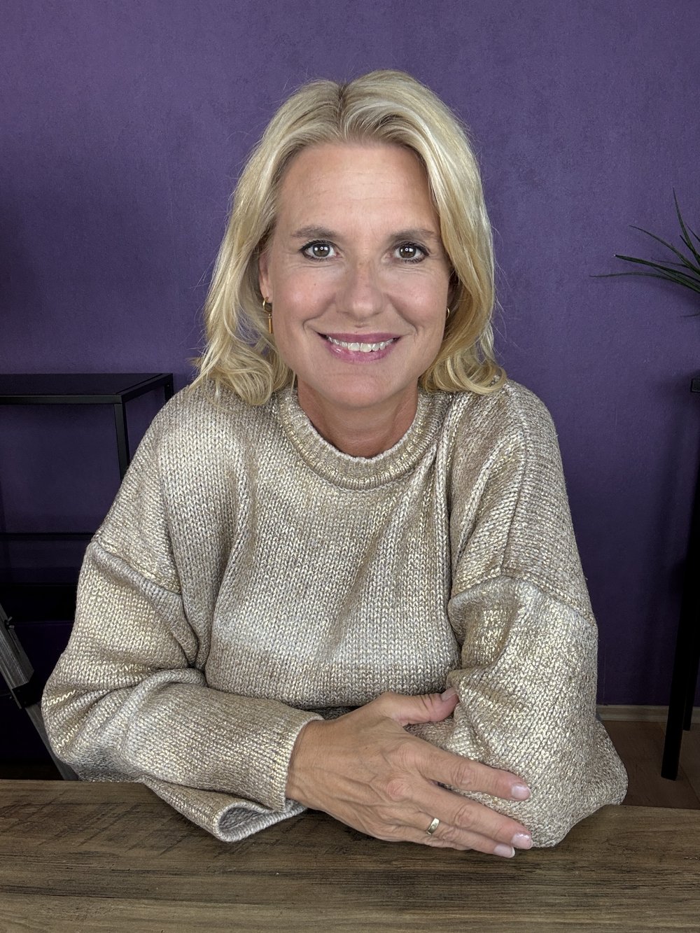 Birgit Quirchmayr im goldenen Strickpulli am Tisch
